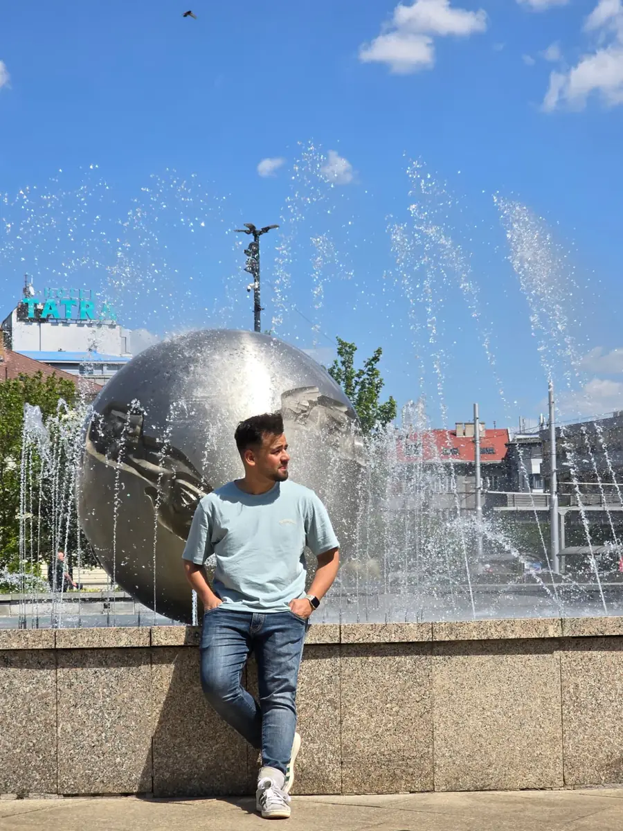Fatik Rahman beside a fountain sculpture in the city centre